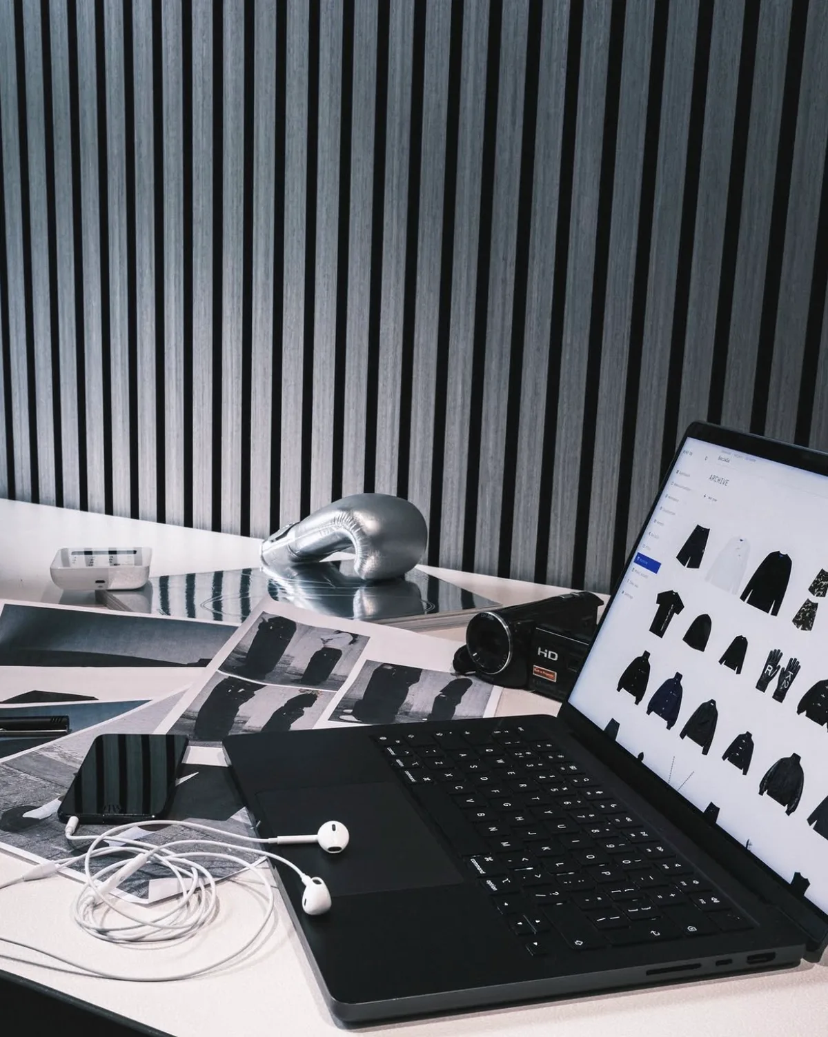 A desk with prints, a camera and the R/K2 archive open on a laptop